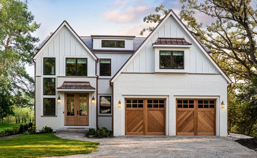 A large white house with two wooden garage doors.