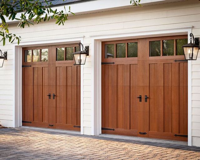 A pair of wooden garage doors on a white house.