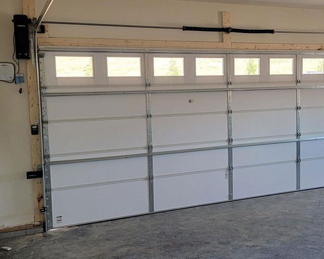 A garage door with a lot of windows is open in a garage.