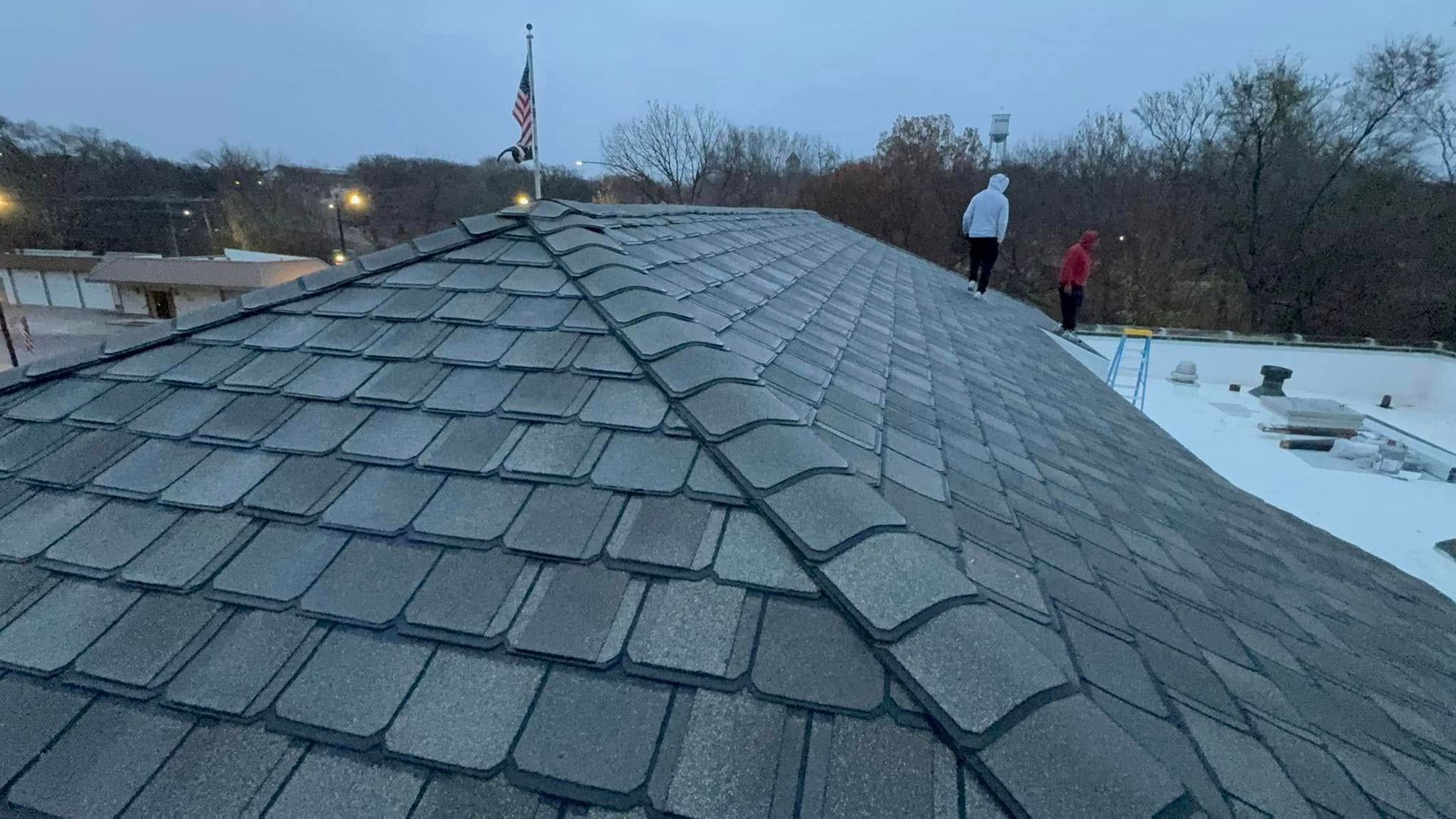 A person is standing on top of a roof in the snow.