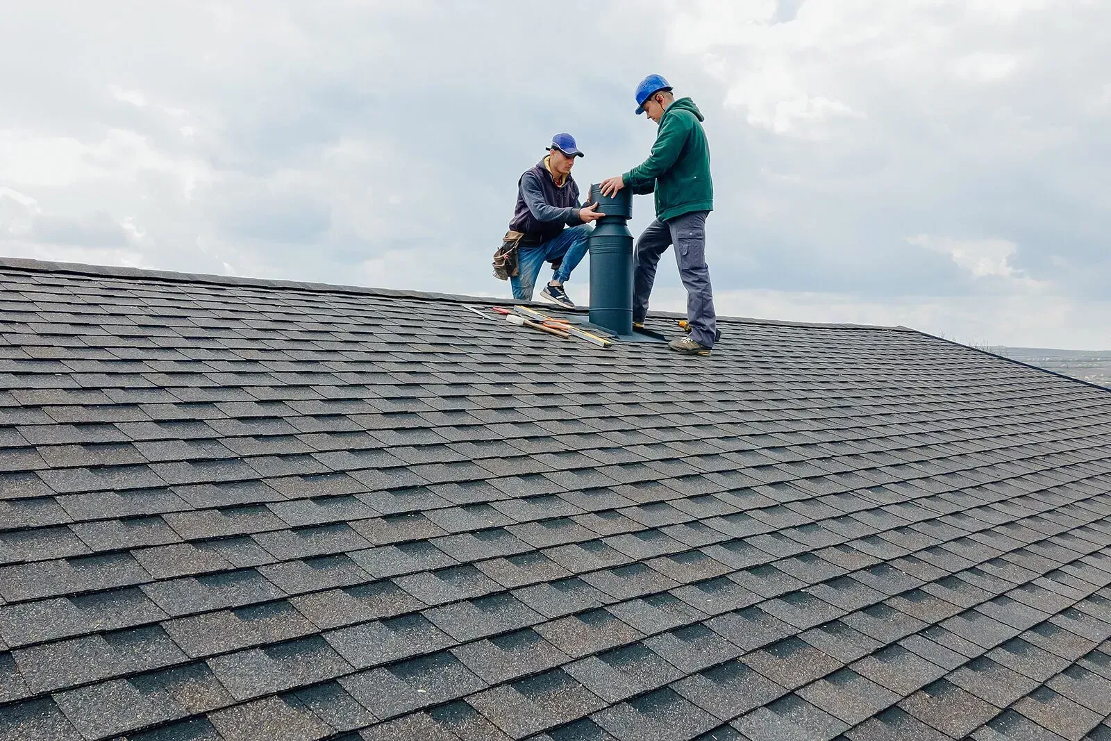 Two men are working on the roof of a house.
