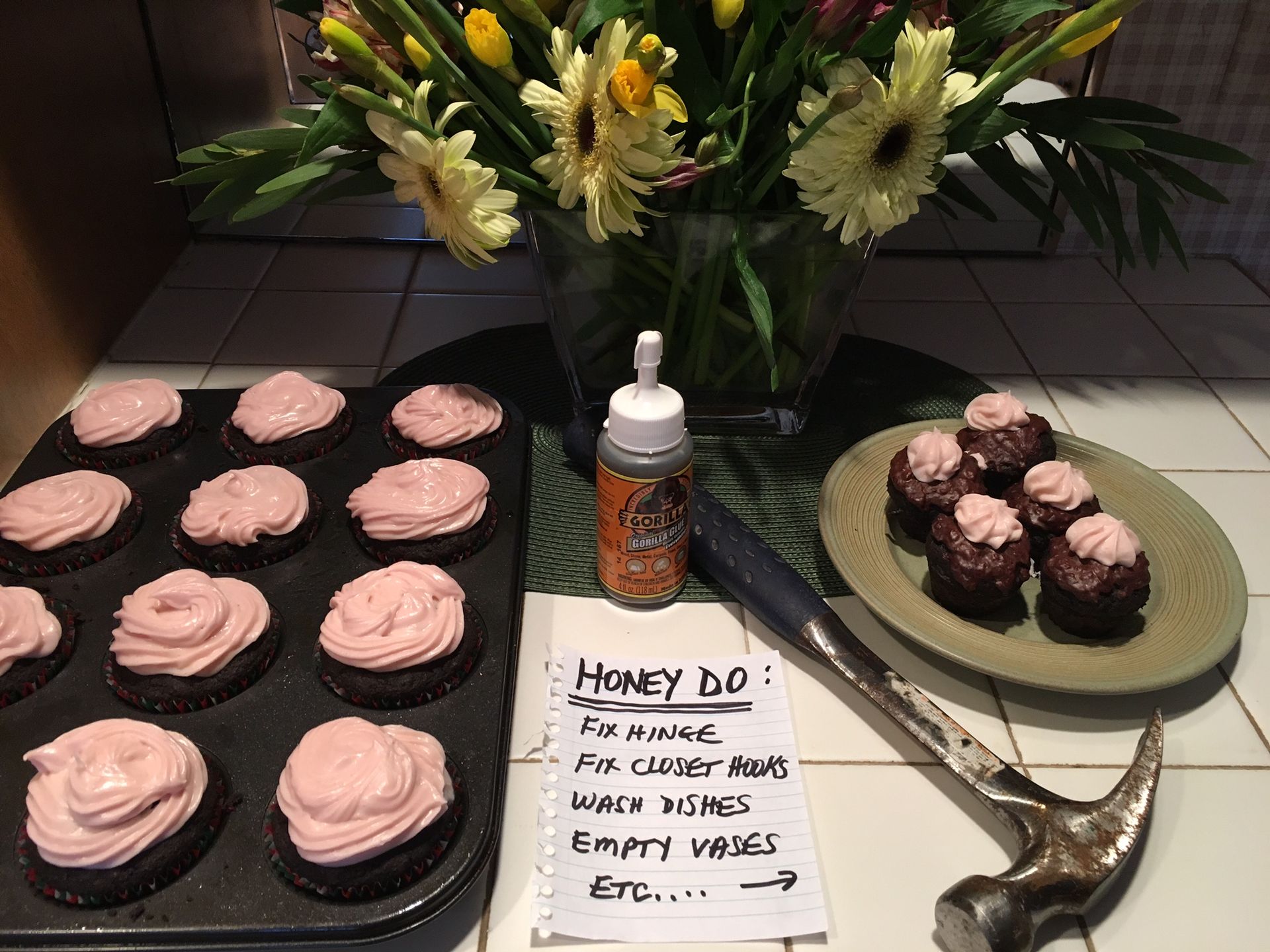 A Tray of Cupcakes With Pink Frosting Next to a Hammer and a Vase of Flowers — Portsmouth, NH — Lager Susan R