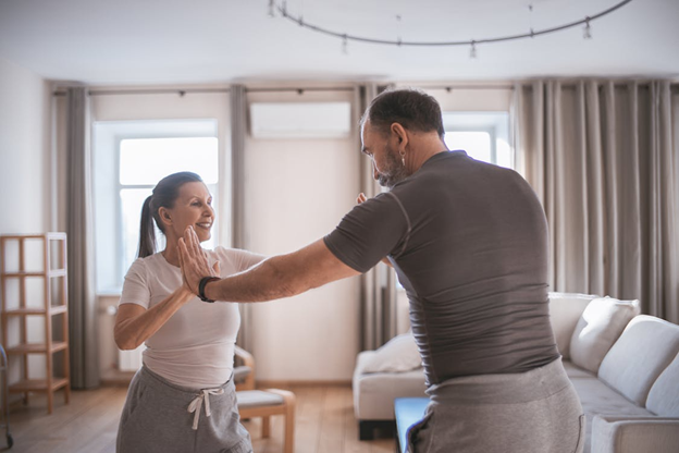 Man and woman high-fiving, in a brightly lit living room.