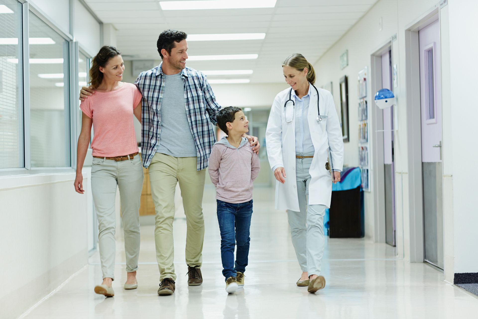 A doctor is walking with a family in a hospital corridor.