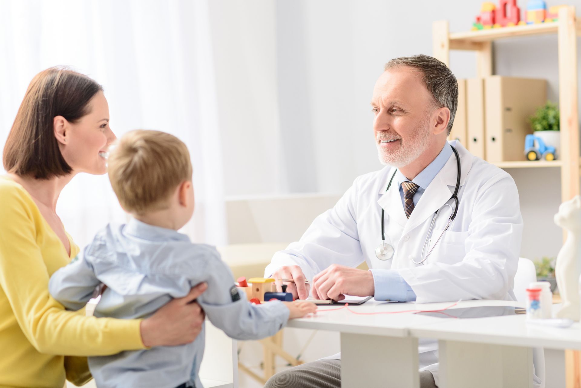 A doctor consulting a patient with a child in a clinic.