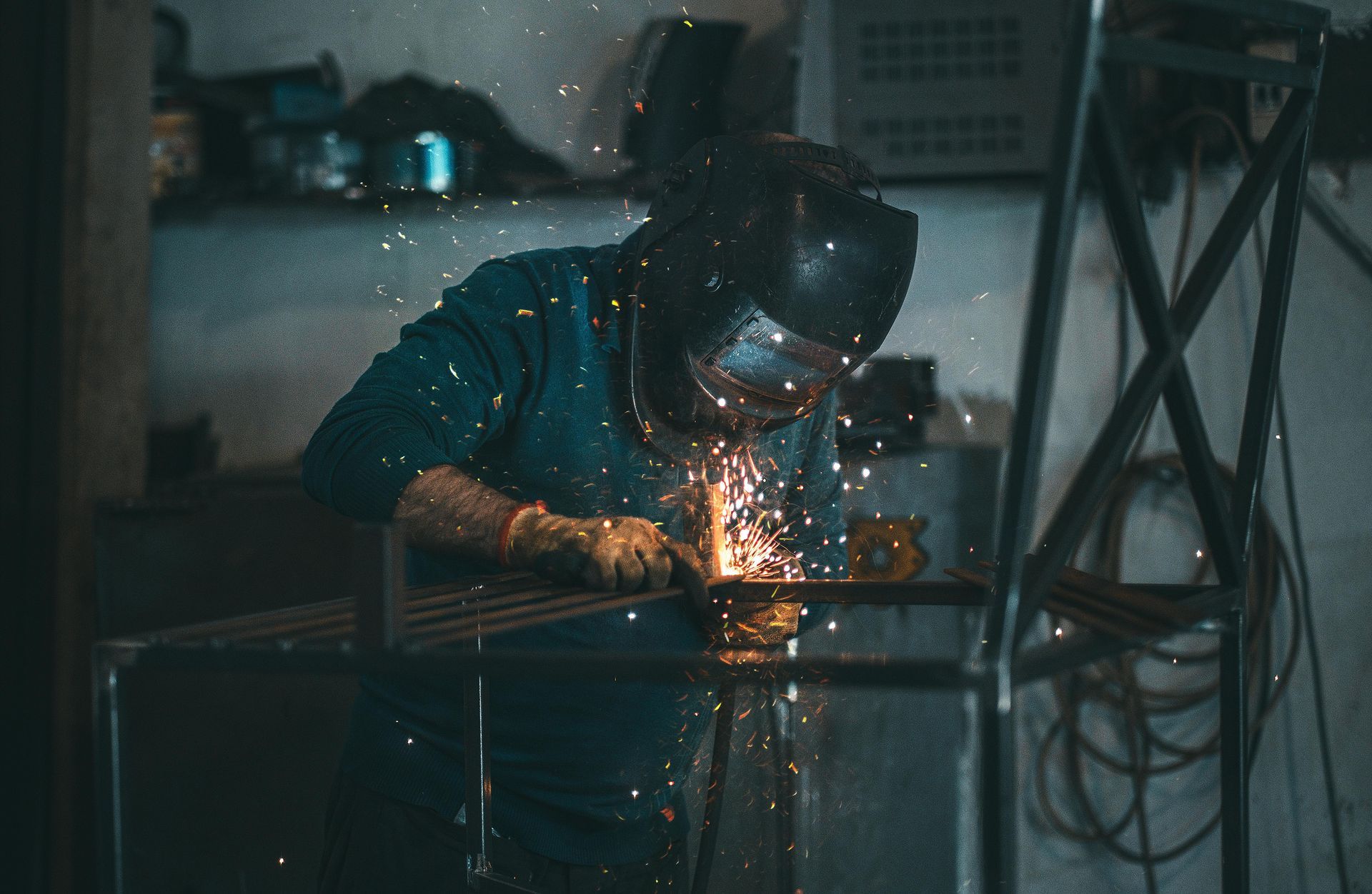 A man is welding a piece of metal in a garage.