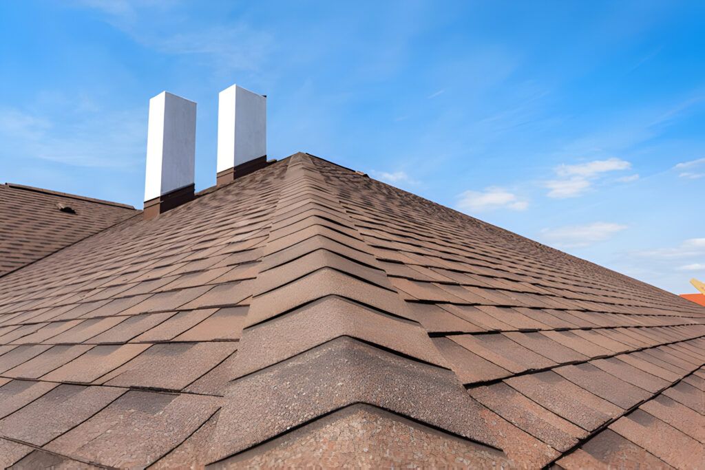 A roof with two chimneys on it and a blue sky in the background.