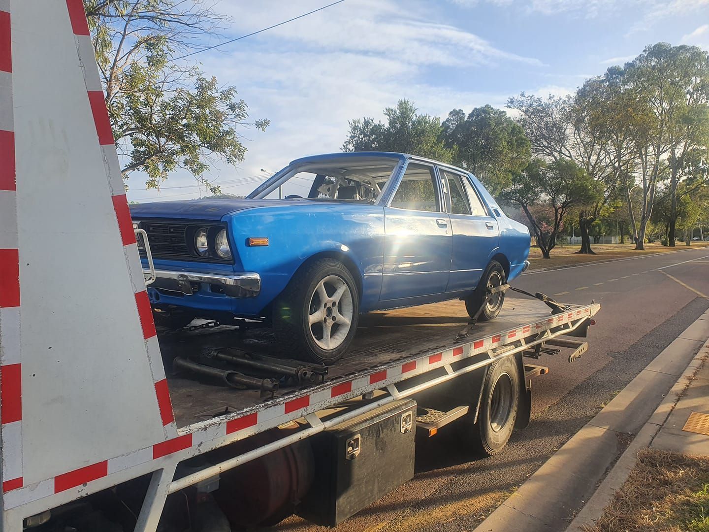 A blue car is being towed by a tow truck.