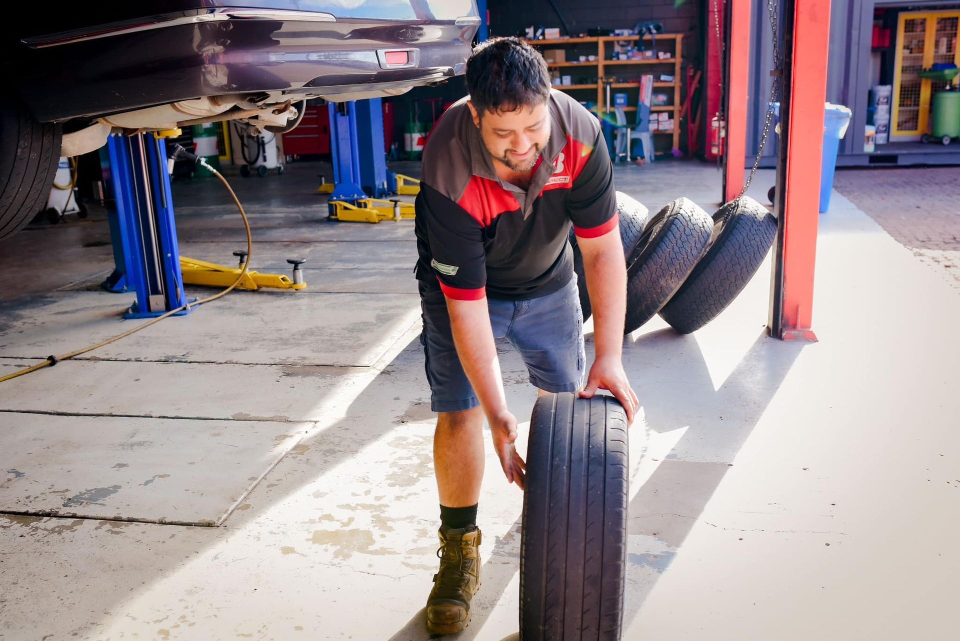 A man is changing a tire in a garage.
