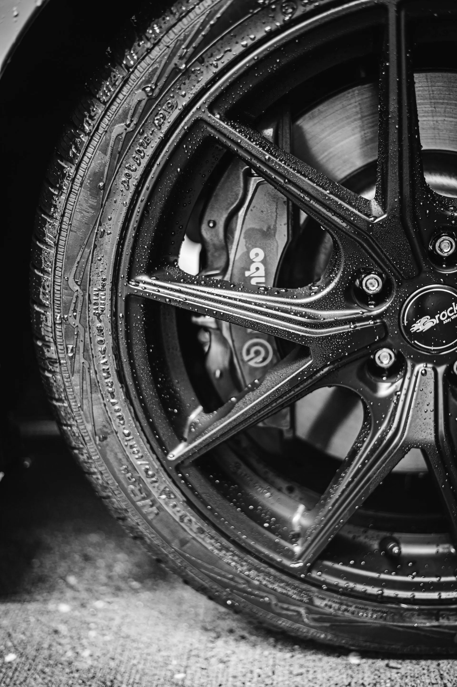 A black and white photo of a car wheel with a brembo brake.