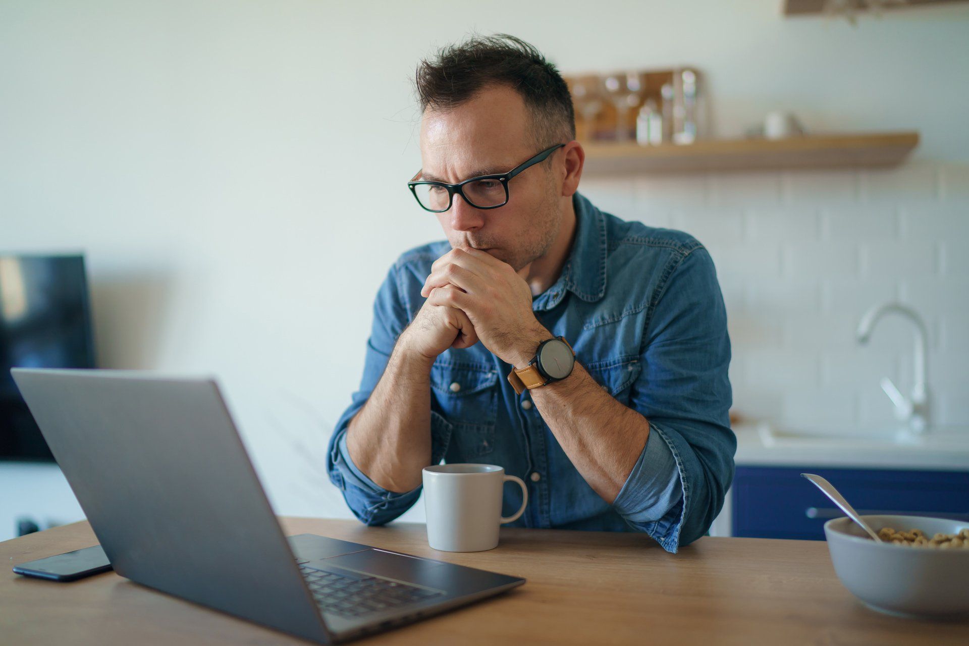 A man is sitting at a table using a laptop computer.