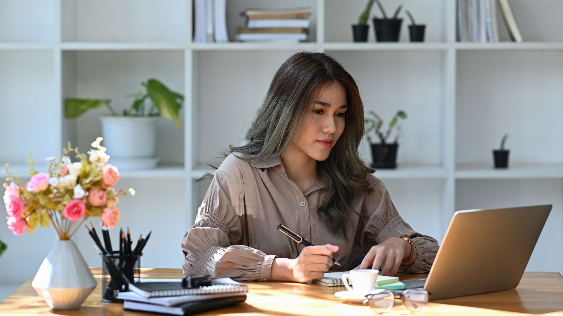 A woman is sitting at a desk using a laptop computer.