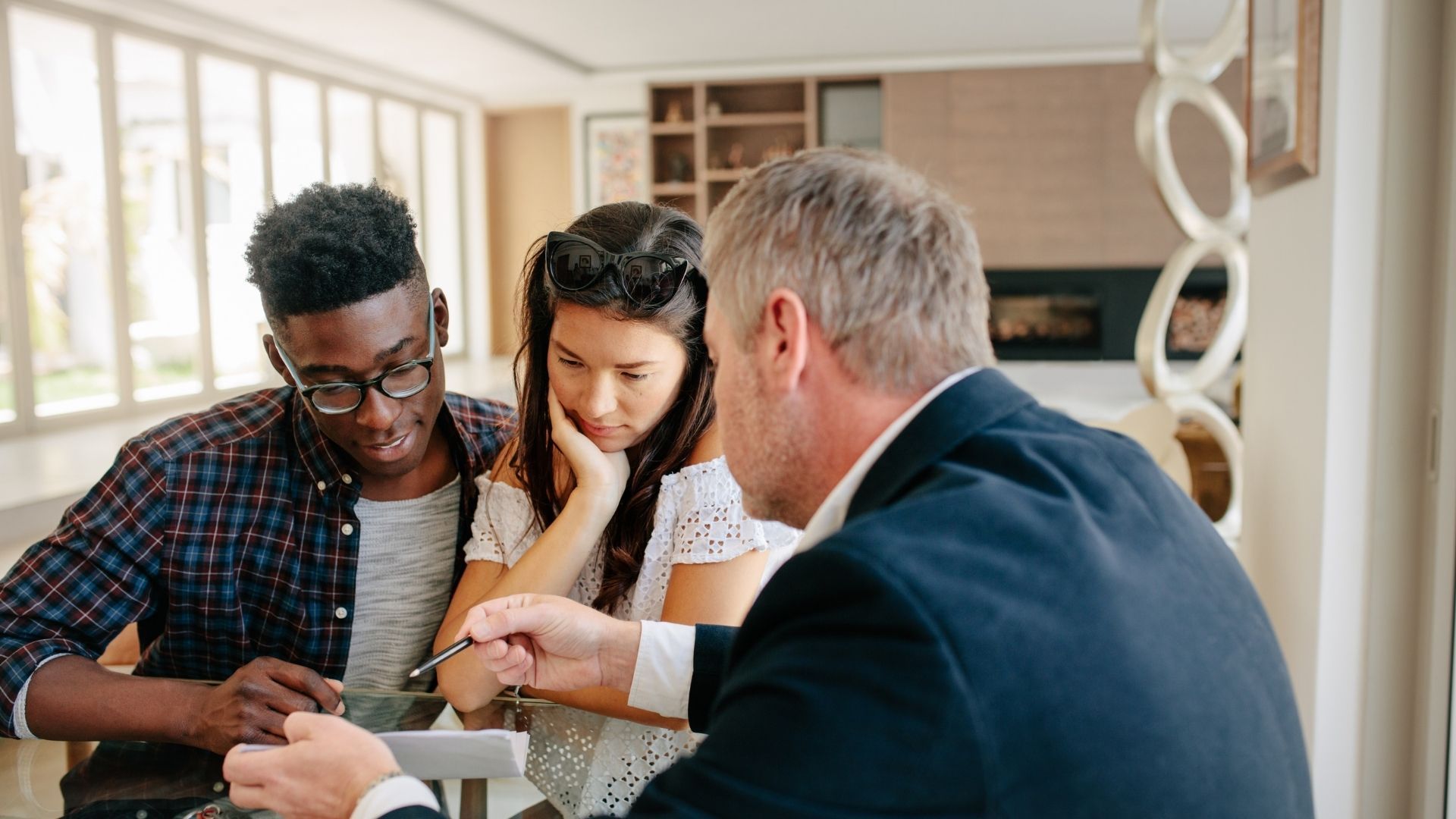 A man and a woman are sitting at a table talking to a real estate agent.