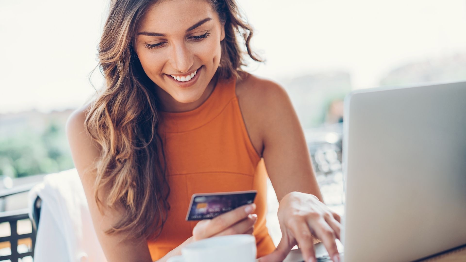 A woman is holding a credit card and using a laptop computer.