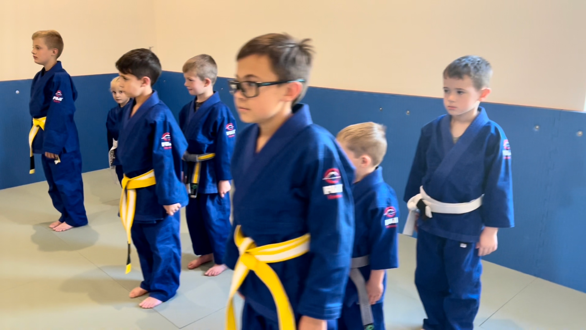 A group of young boys in karate uniforms are standing in a room.