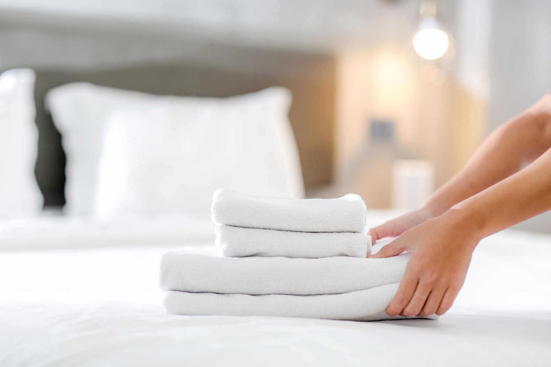 a person is stacking towels on top of each other on a bed