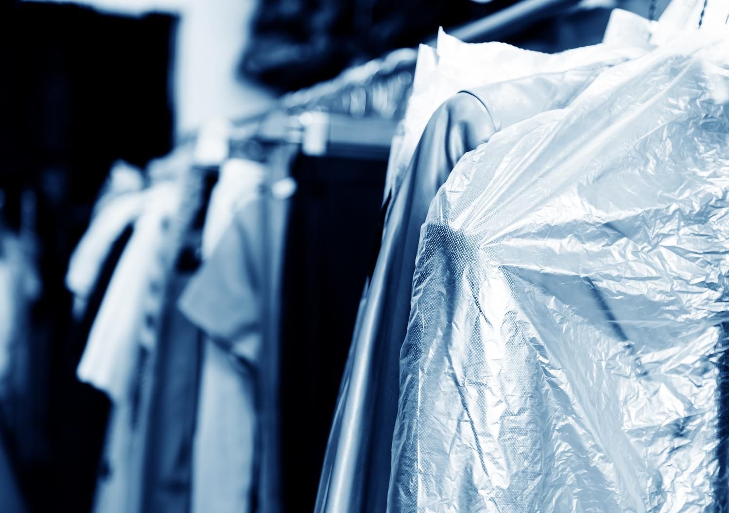 a row of clothes hanging on a rack wrapped in plastic bags