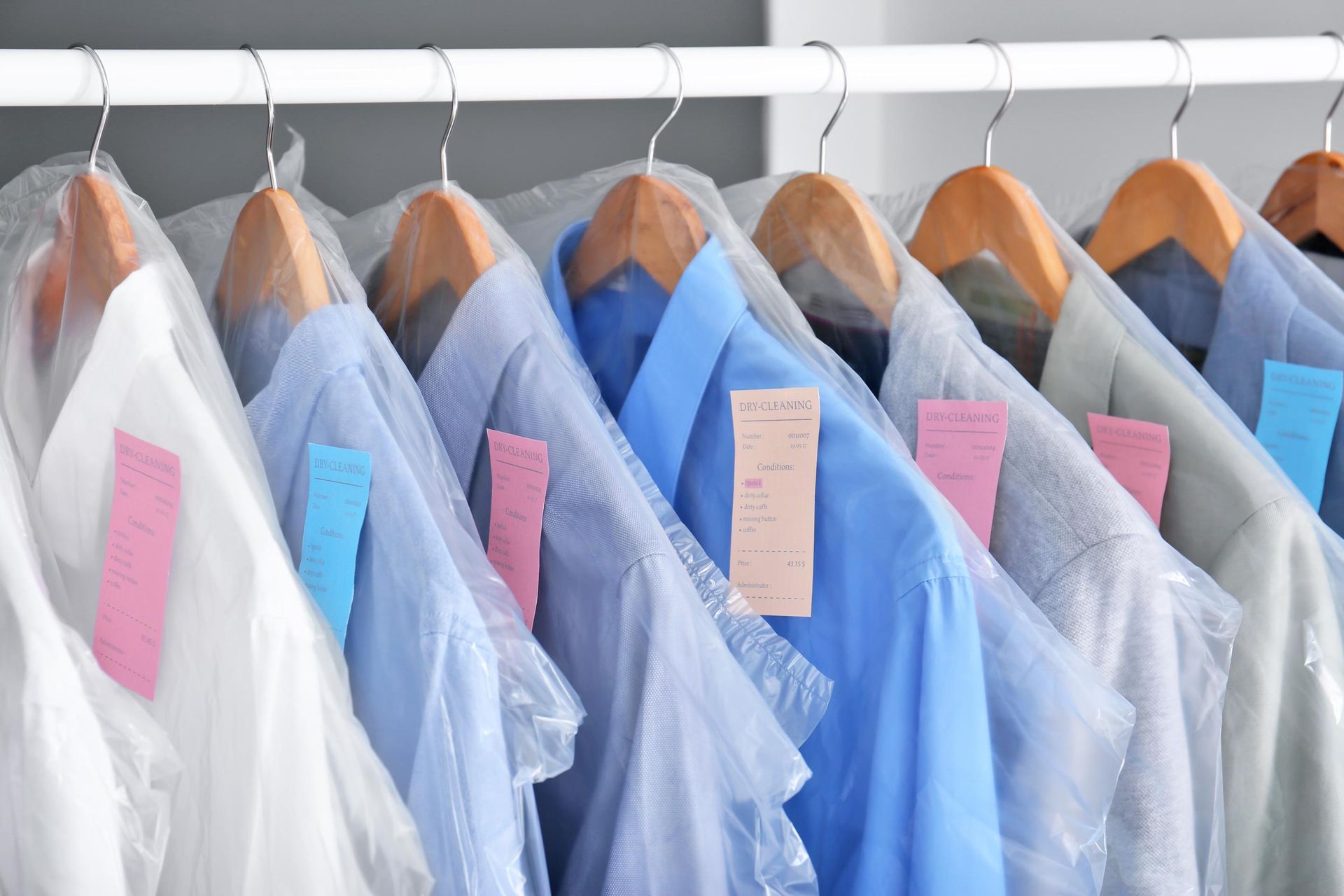 a row of shirts wrapped in plastic are hanging on a rack