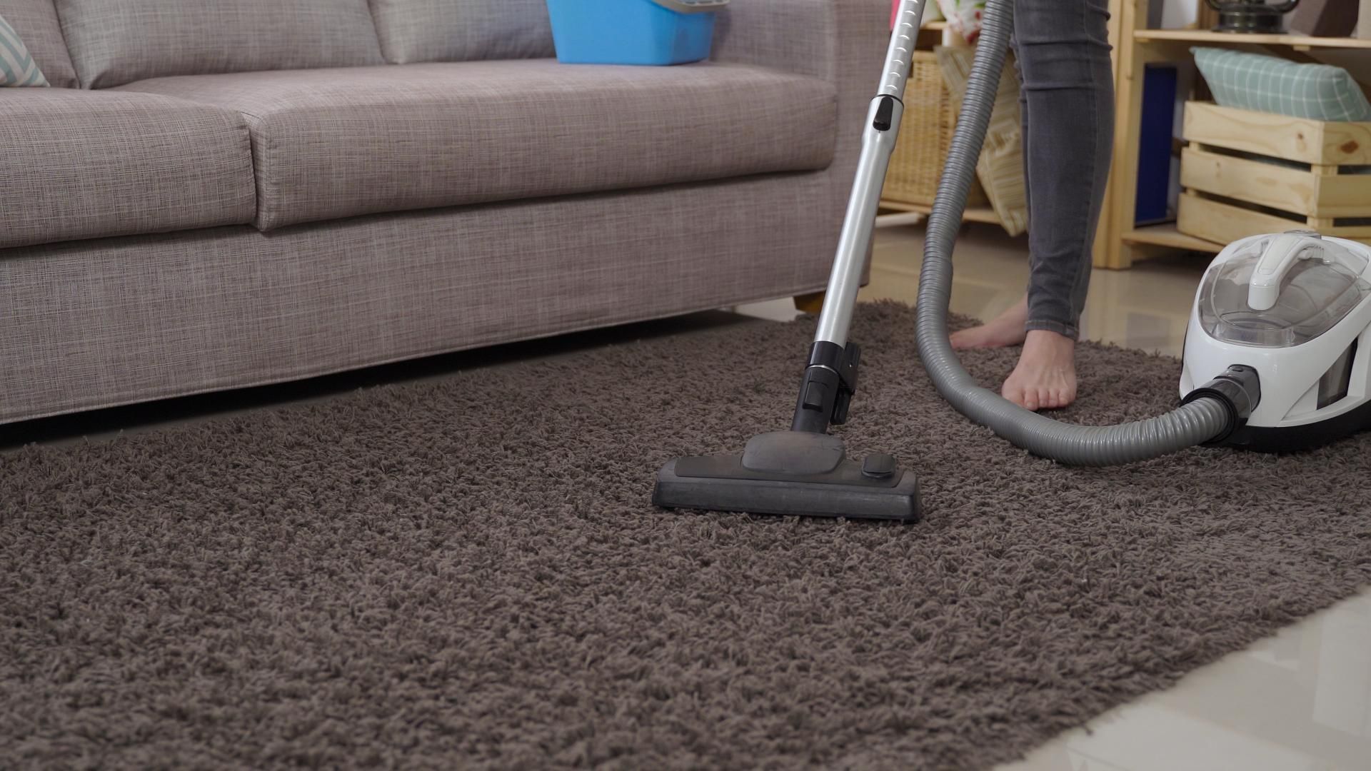 a woman is using a vacuum cleaner to clean a carpet in a living room .