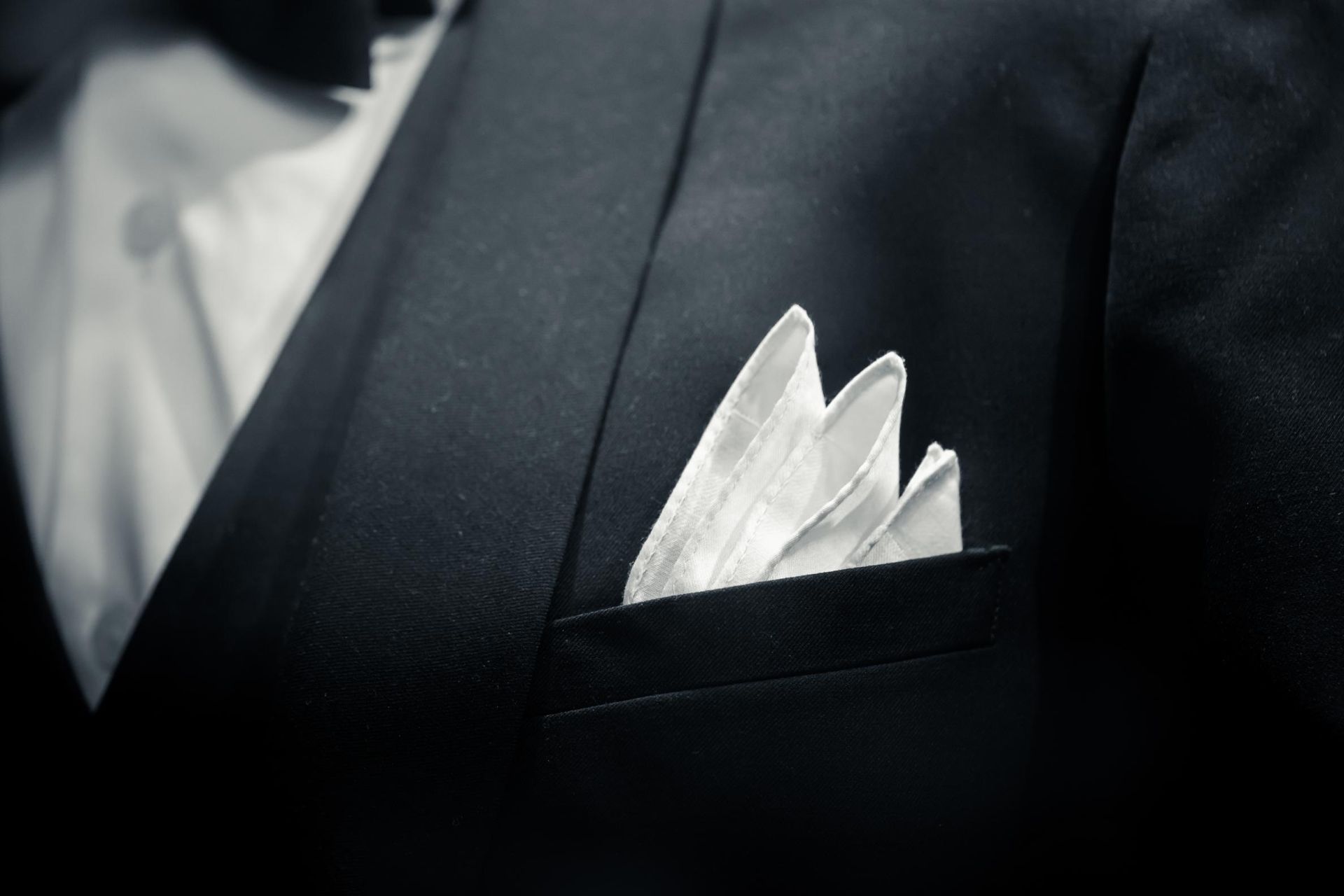 a man in a tuxedo has a white handkerchief in his pocket