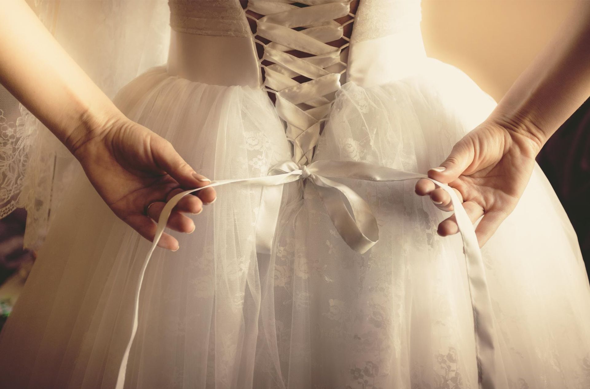 a bride is tying her wedding dress with a ribbon