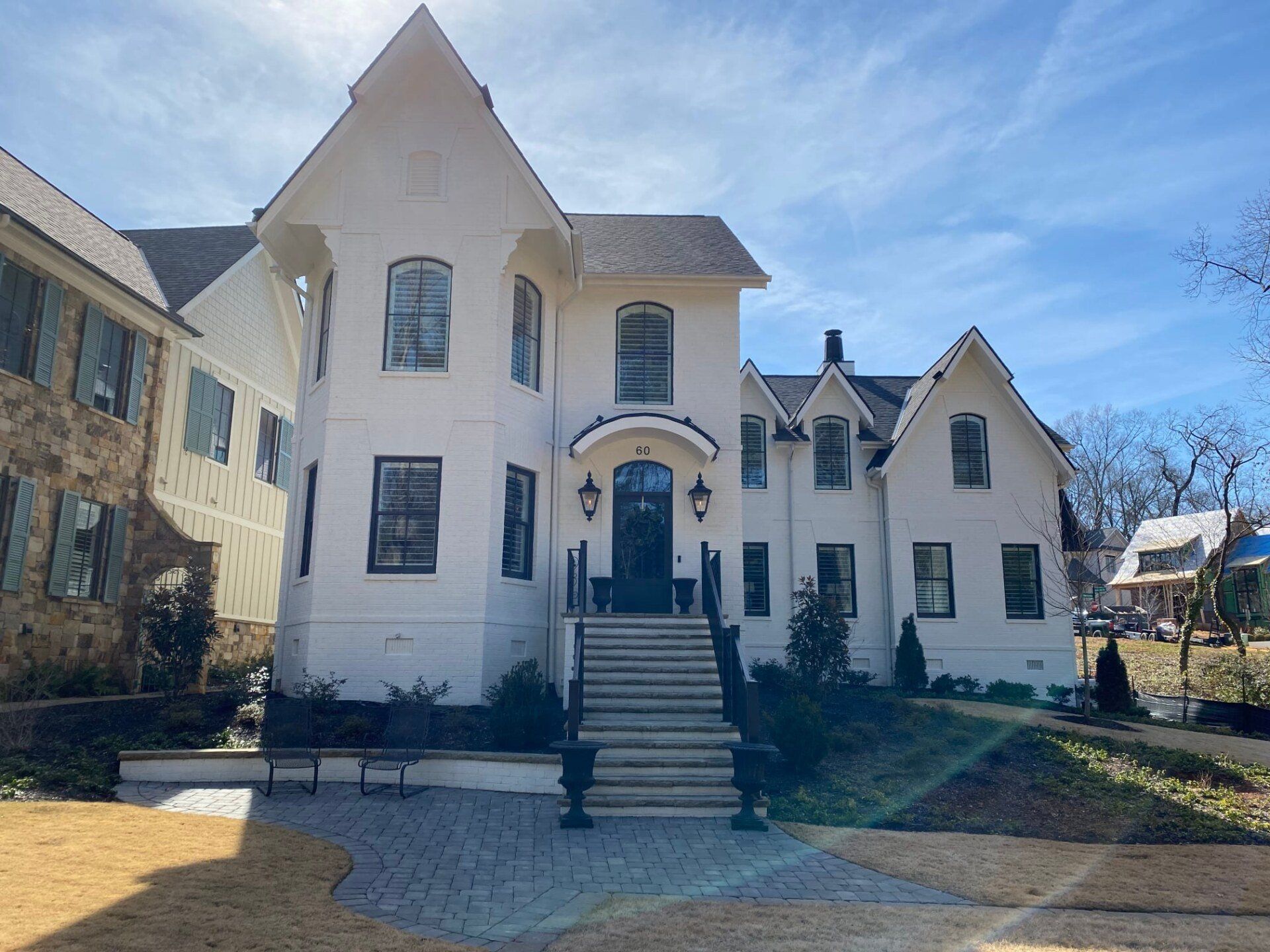 White house with black trim, multiple gables, and steps leading to the front door on a sunny day.