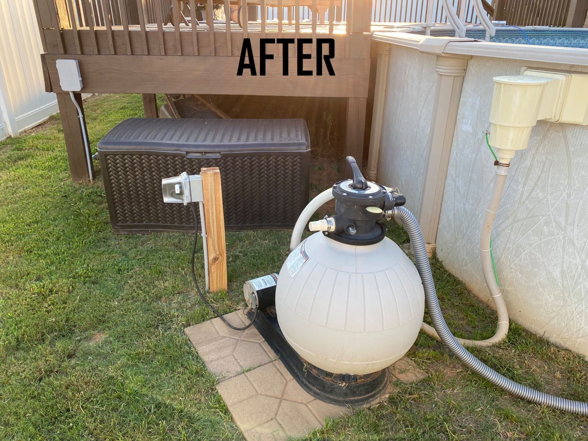 Pool filter system beside an above-ground pool, under a wooden deck.