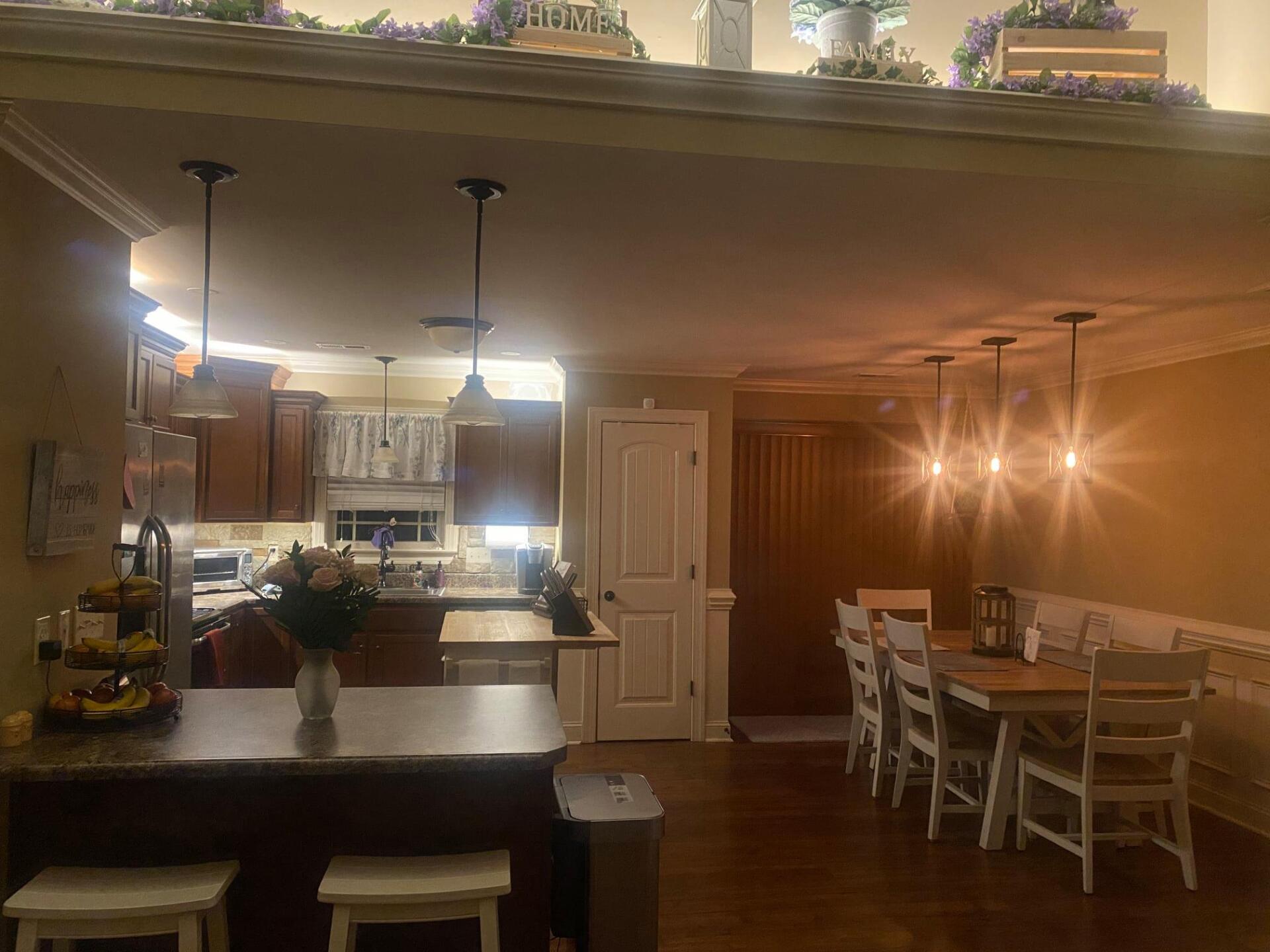 Open kitchen and dining area with pendant lights, dark cabinets, a breakfast bar, and a table set for dining.