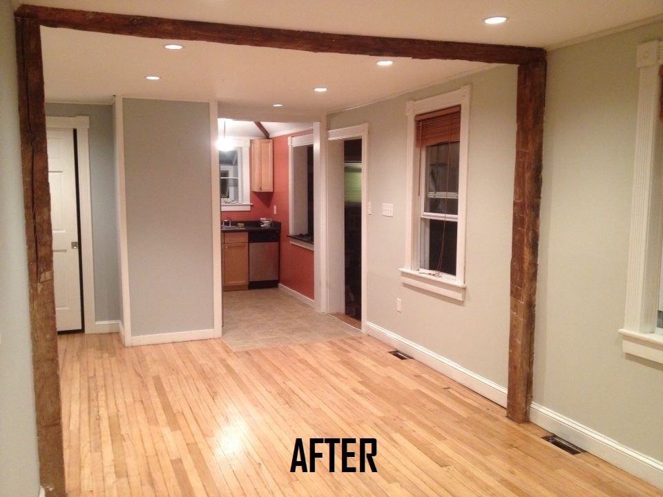 Renovated interior: Light wood floors, exposed beams, gray walls, doorway leads to kitchen.