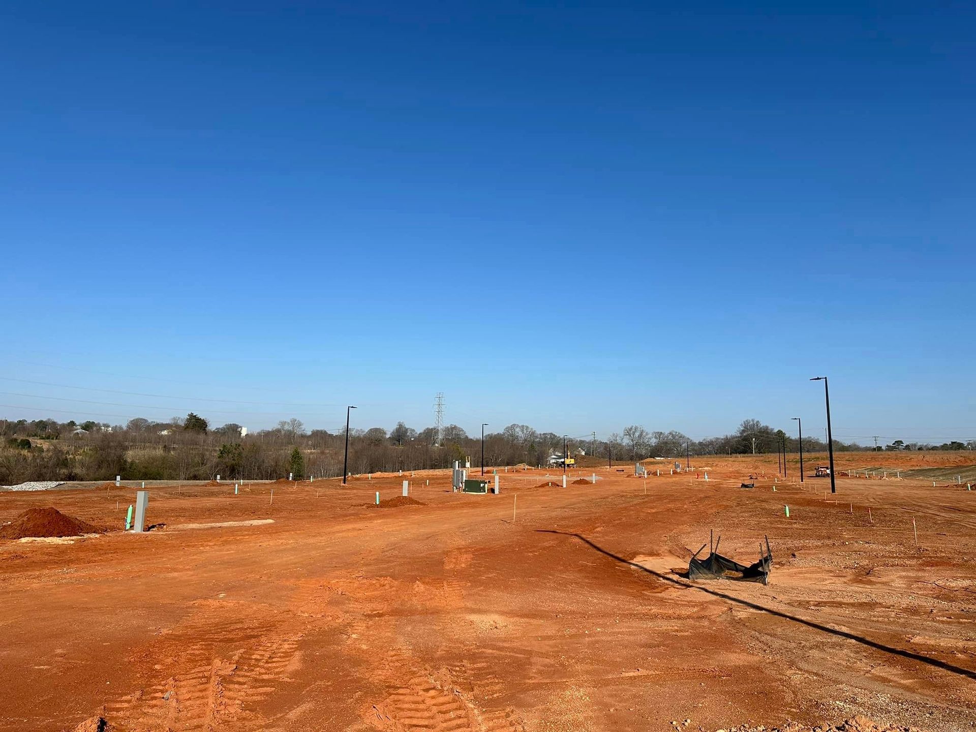 Cleared land for development with red soil under a bright blue sky.