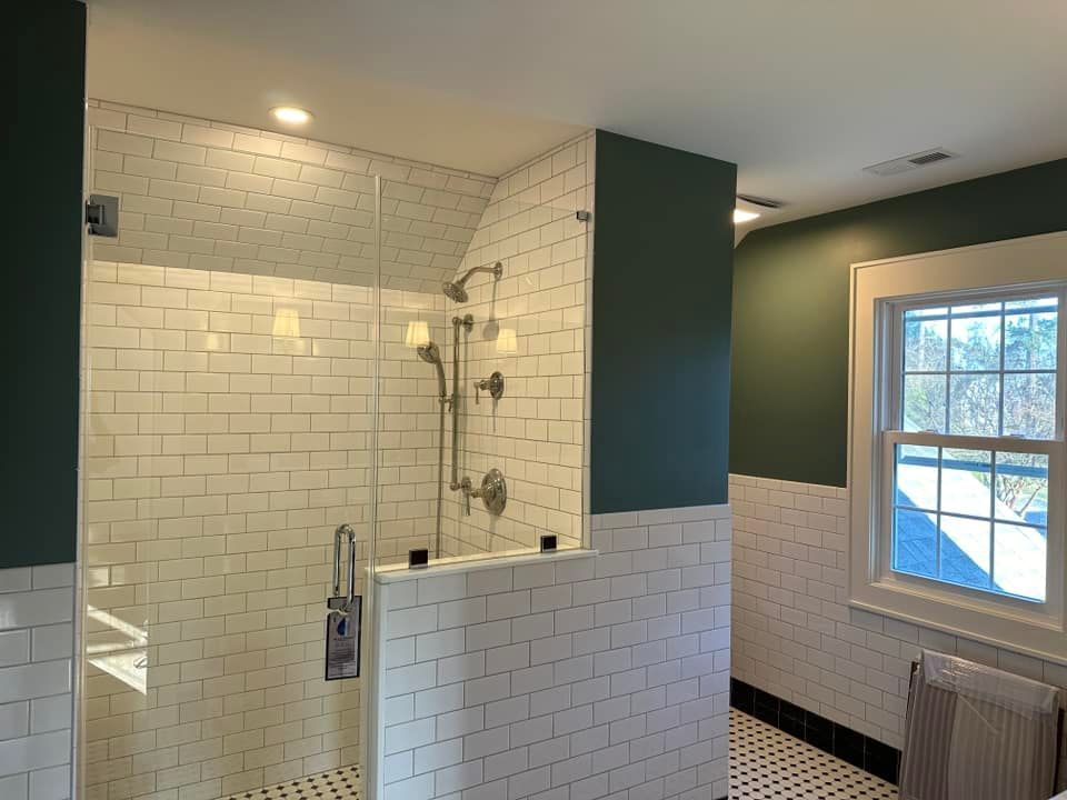 Bathroom with white subway tile, glass shower, and green accent wall.