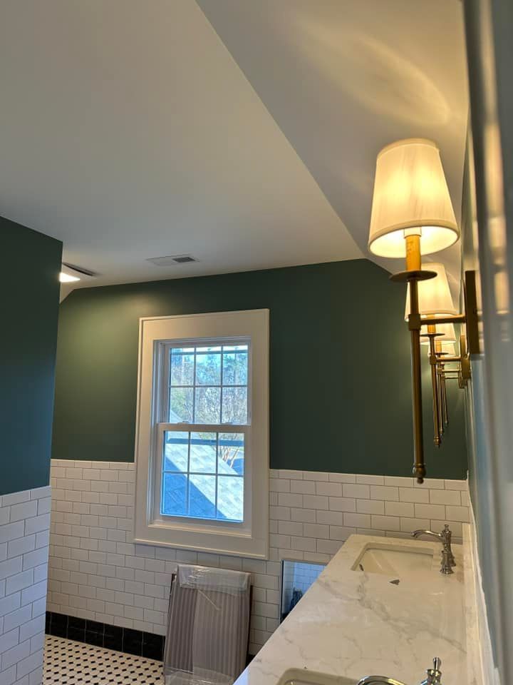 Bathroom with green walls, white subway tile, a window, and sconce lighting.