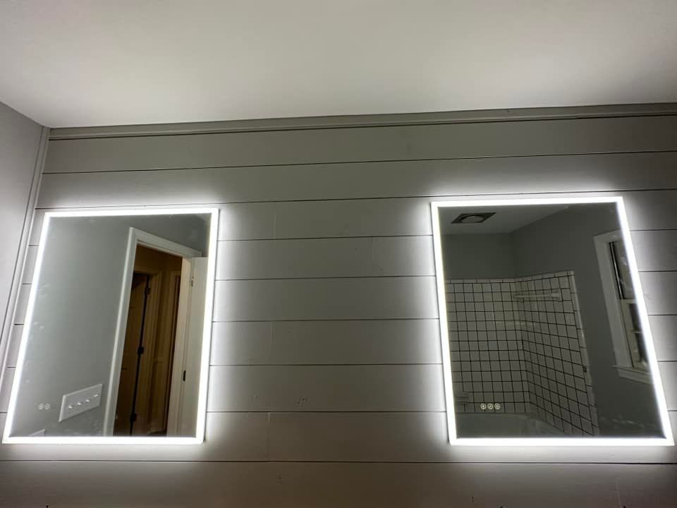 Two rectangular mirrors with built-in white LED lights on a gray planked wall.