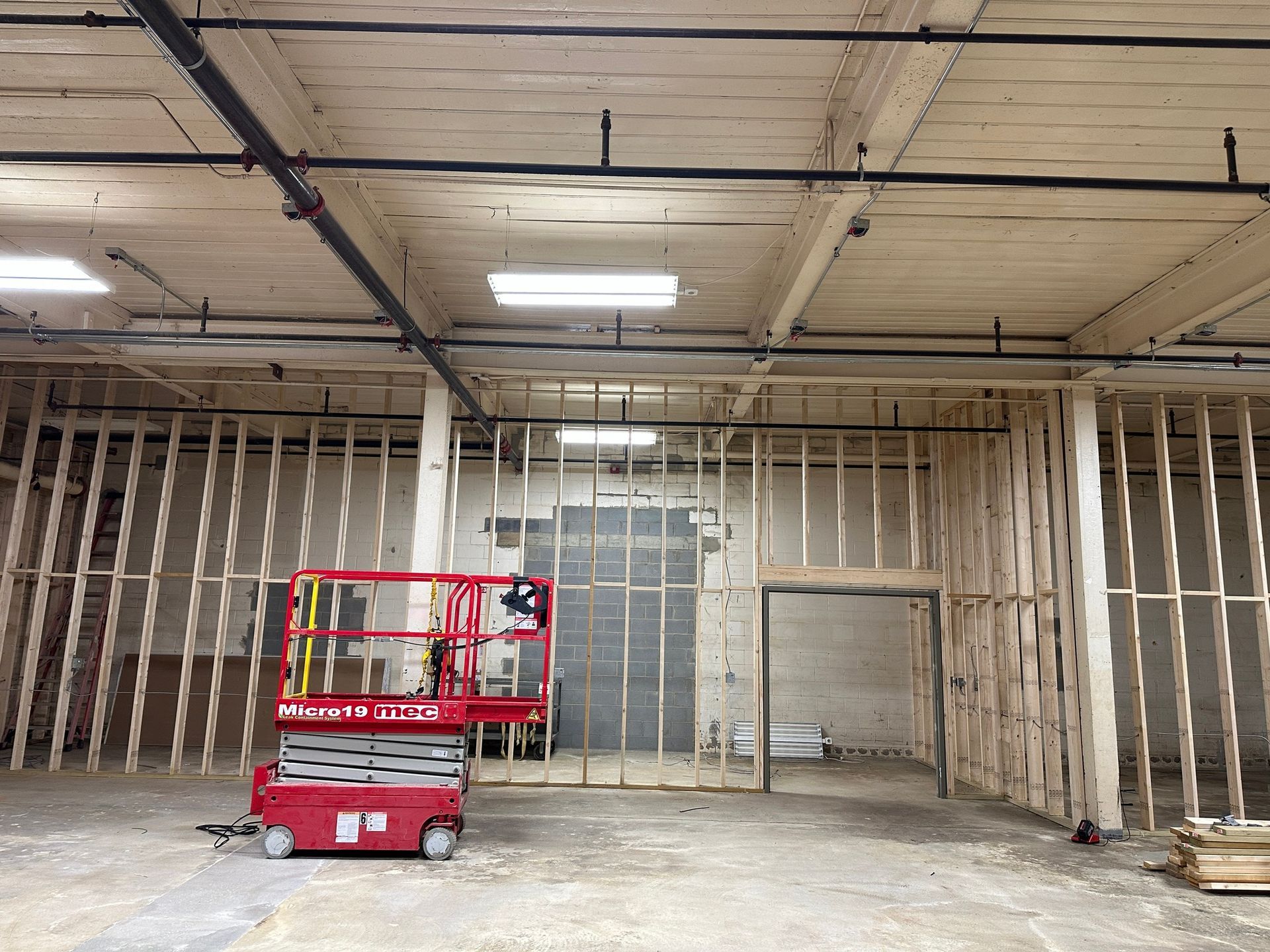 Interior construction with wooden framing and a red lift.