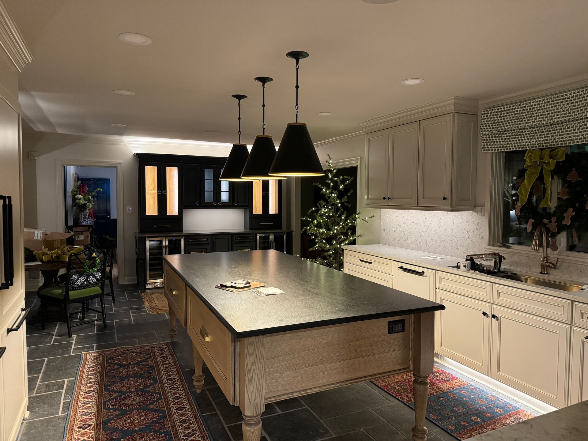 Kitchen with a large island, pendant lights, cabinets, and a rug.