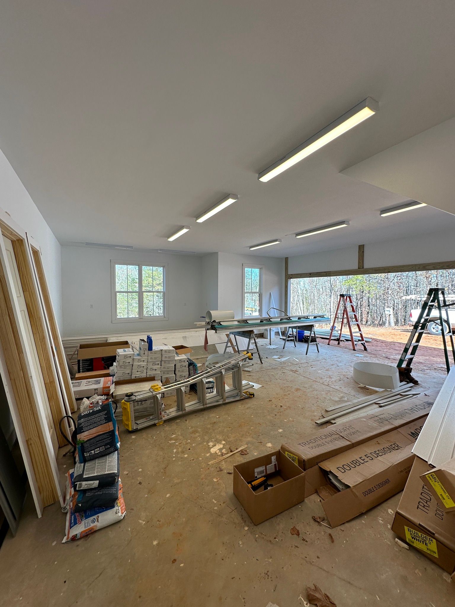 Interior of a room under construction, with open boxes, tools, and construction materials scattered around.