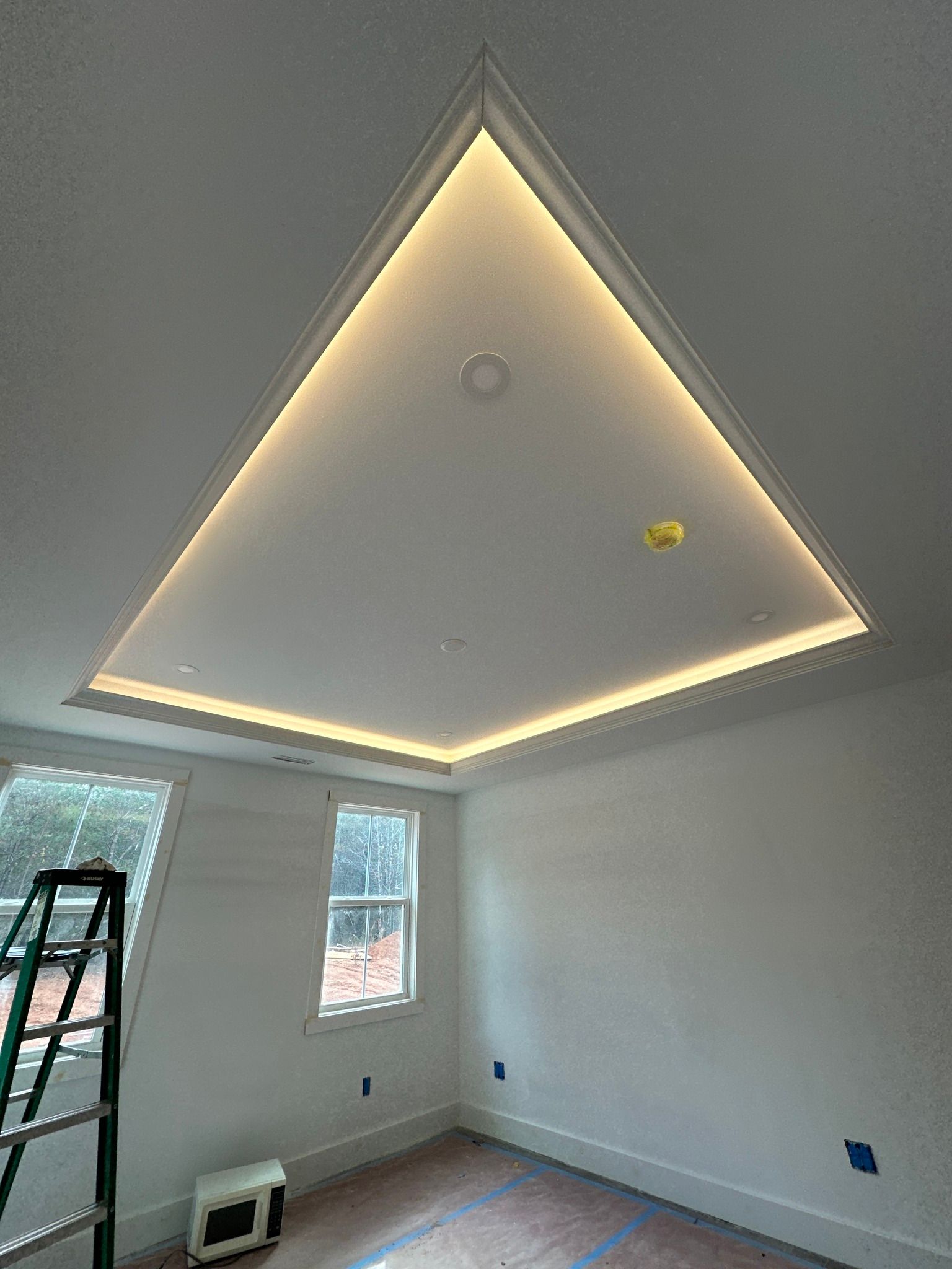 Ceiling with recessed lighting, rectangular shape, with a ladder and window on the left.