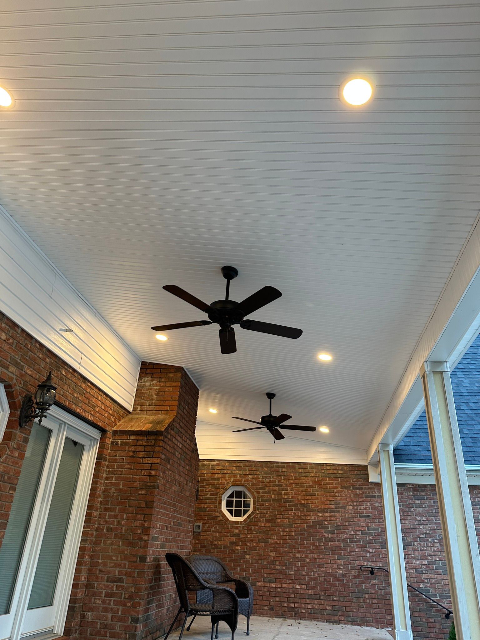 Covered patio with brick wall, ceiling fans, recessed lights, and a brick chimney.