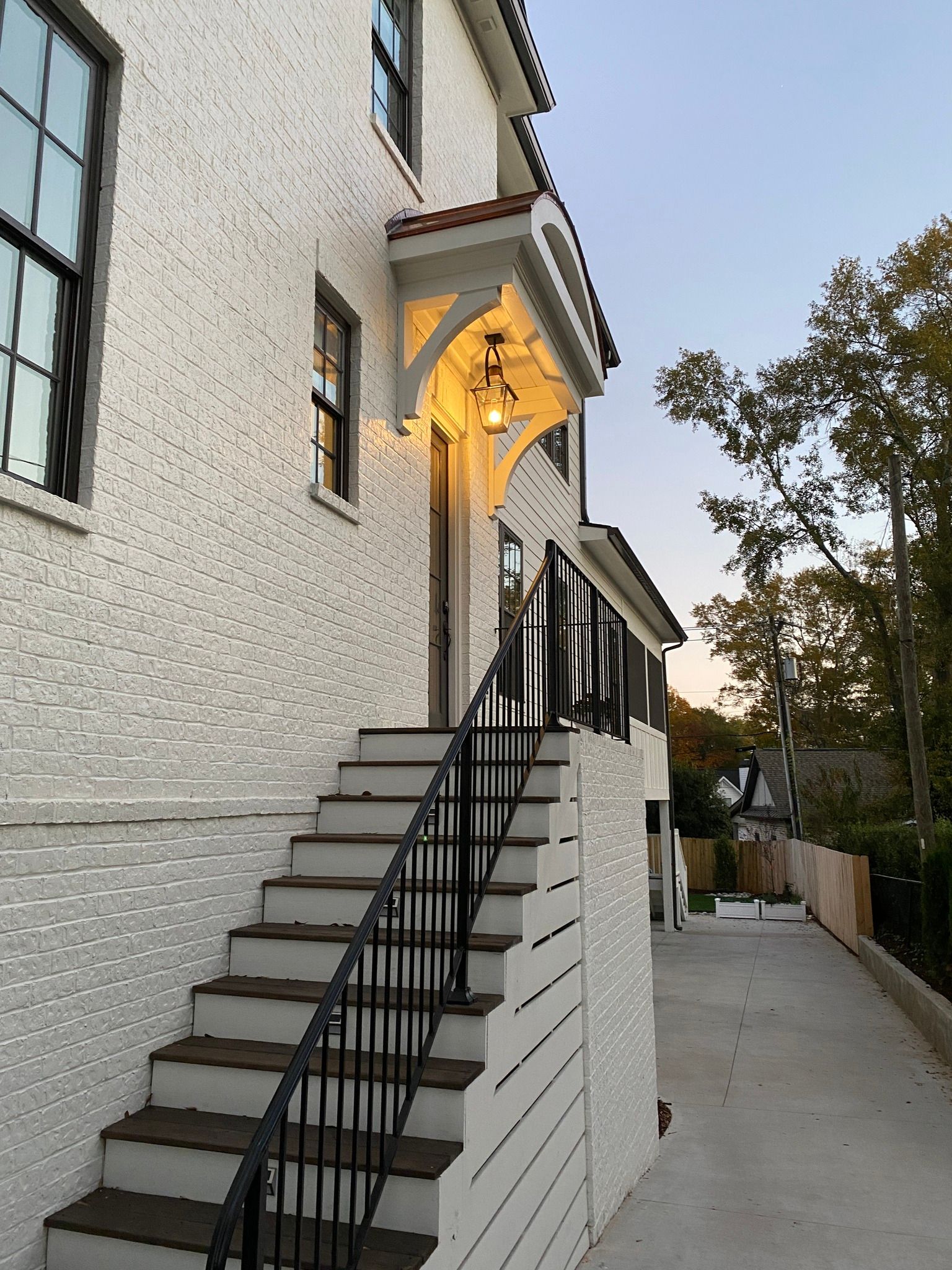 Exterior view of a white stucco house with stairs leading to a doorway under a small roof.