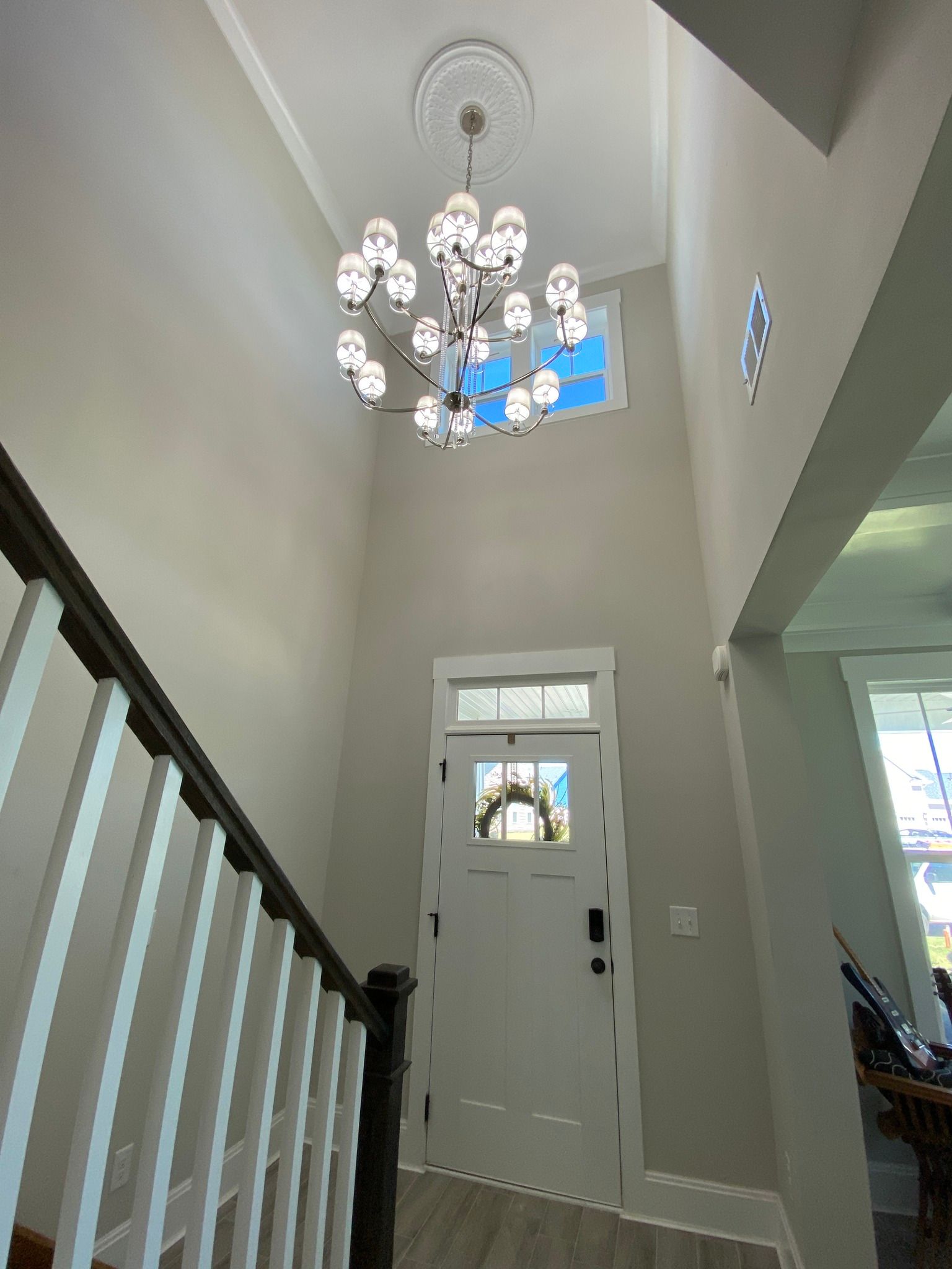 Entryway with high ceiling, chandelier, staircase, and white front door.