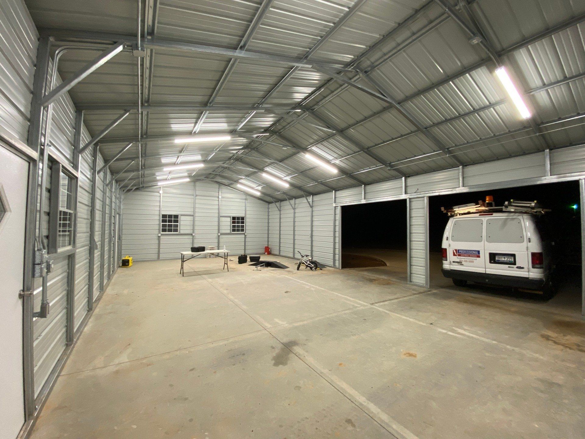 Inside of a metal garage with a white van parked in one bay.