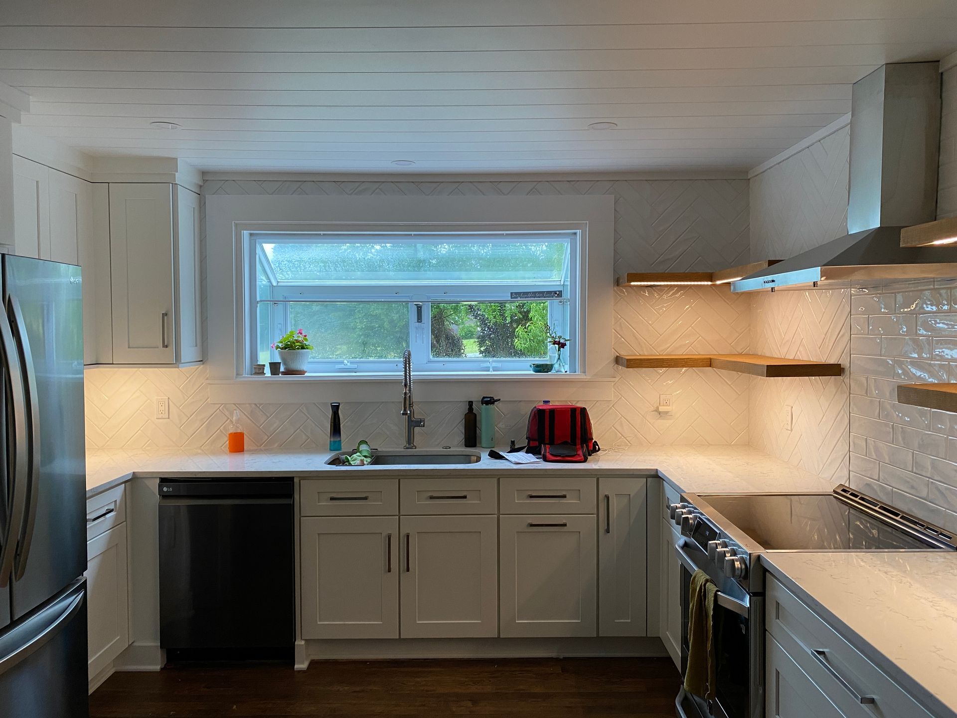 White kitchen with stainless steel appliances, white cabinets, and wooden shelves.