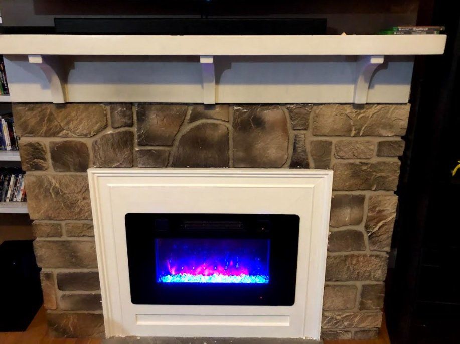 Electric fireplace with blue and purple flames, built into a stone and white mantle.