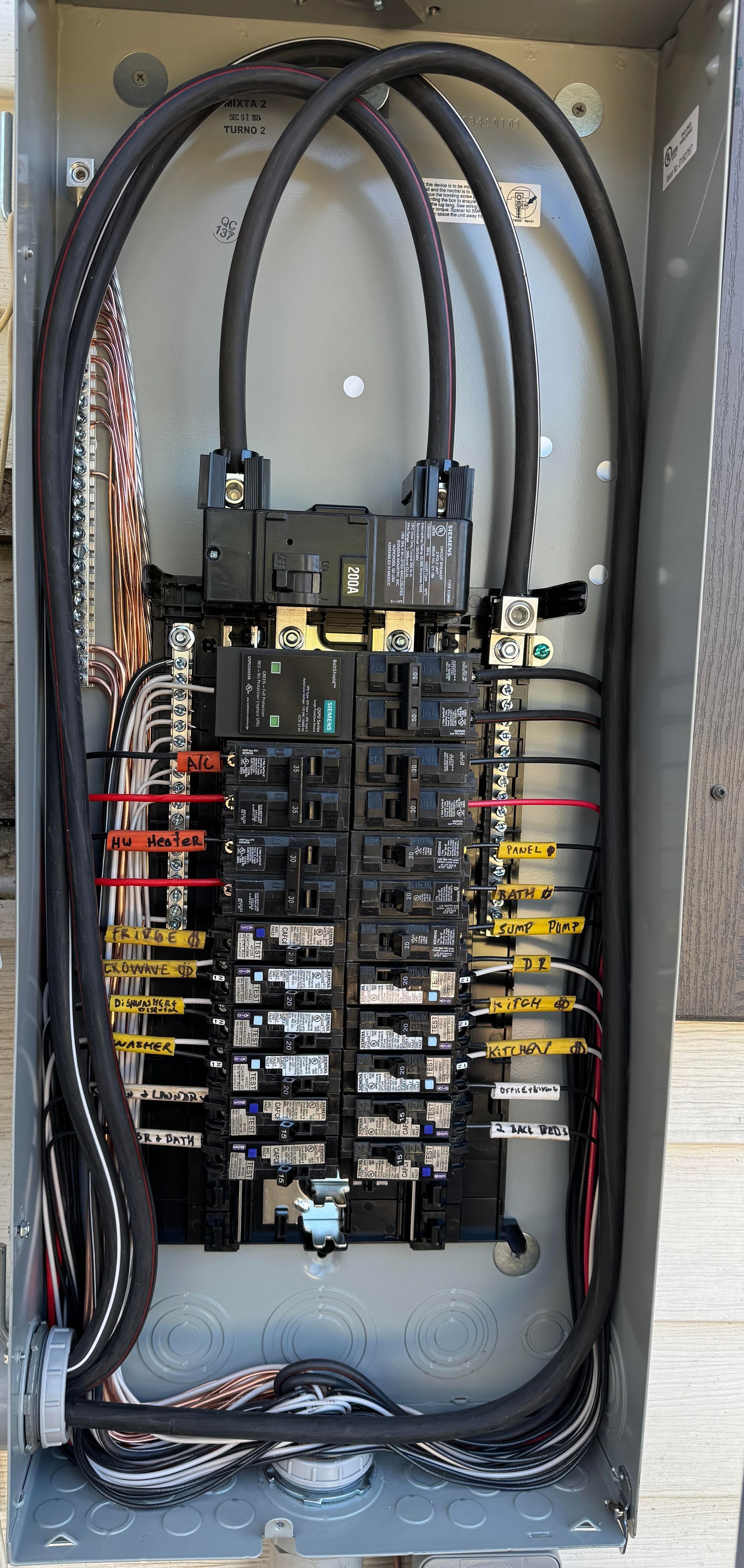 Electrical panel with circuit breakers and wiring inside a metal enclosure.