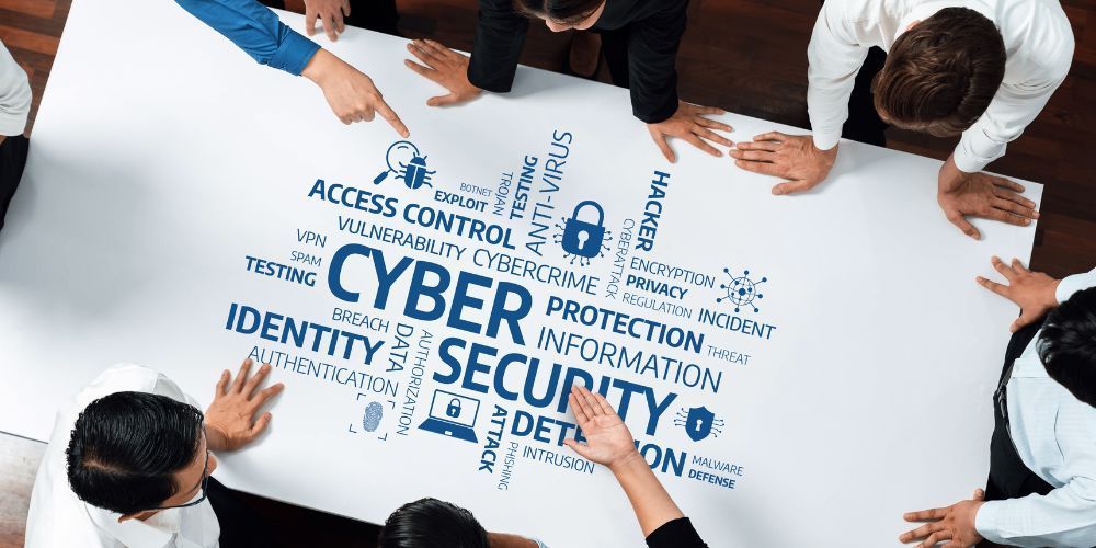 A group of people standing around a table with a white sheet featuring a blue word cloud about cybersecurity.