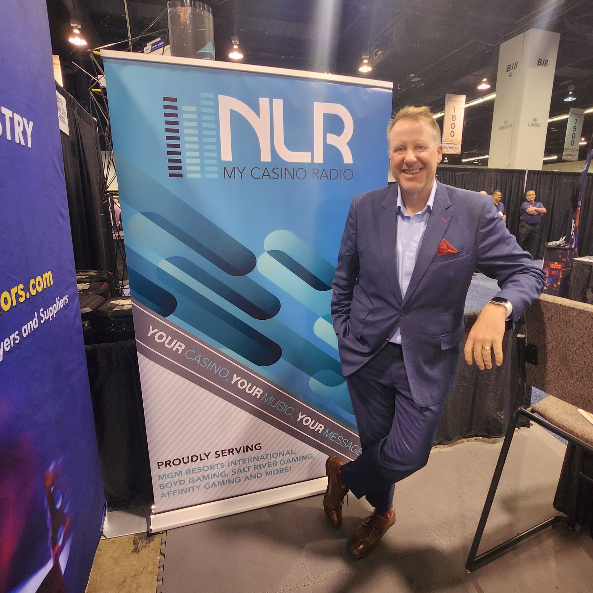 A man in a suit stands in front of a sign that says nlr