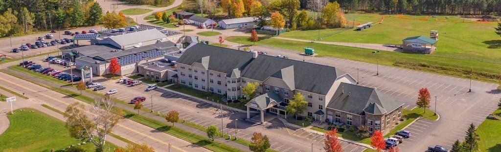 An aerial view of a large building with a lot of cars parked in front of it.