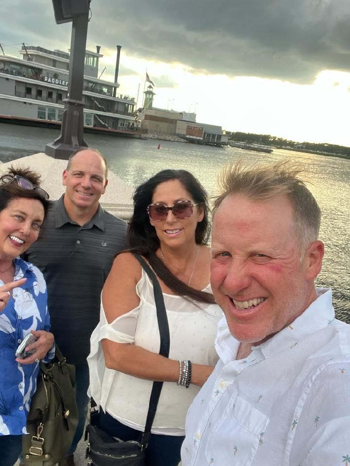 A group of people are posing for a picture in front of a body of water.