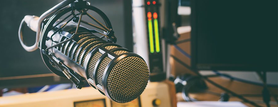 A close up of a microphone hanging from a stand in front of a computer.