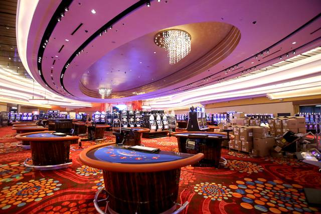 A casino with tables and a chandelier on the ceiling